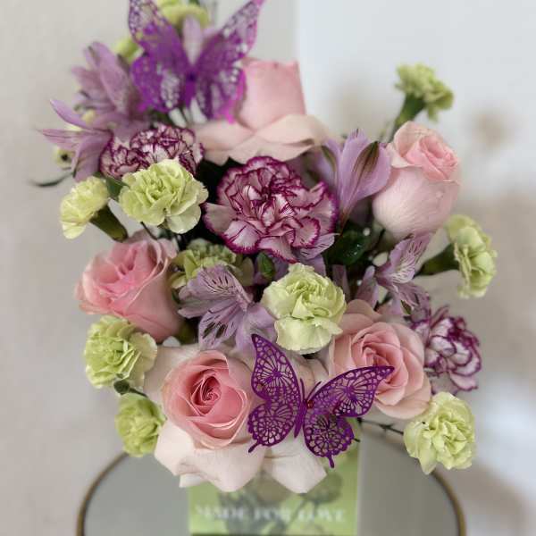 Pink roses and purple carnations in a box with butterfly decorations