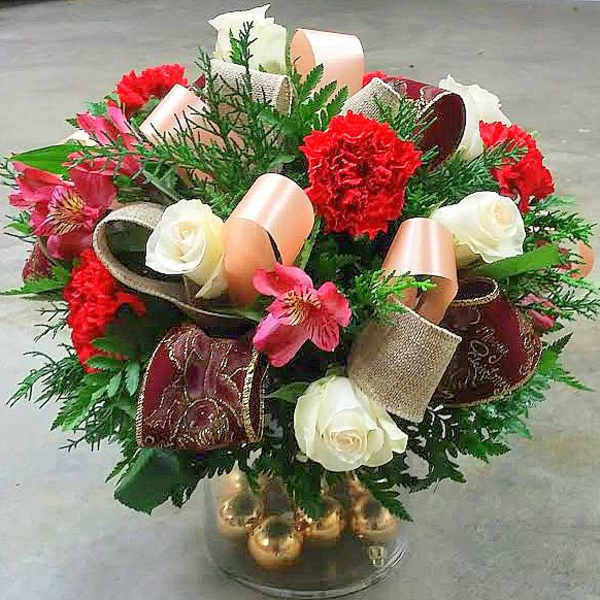 Bouquet of red carnations, white roses, and pink alstroemeria in a glass vase