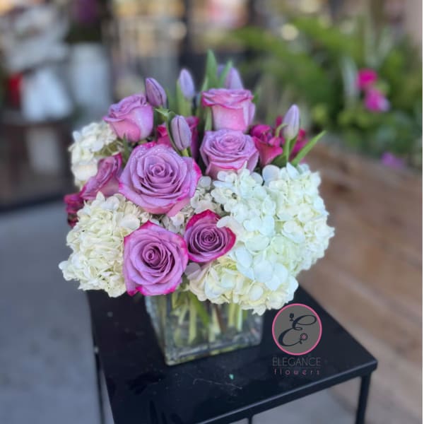 Pink roses and white hydrangeas arranged in a clear square vase