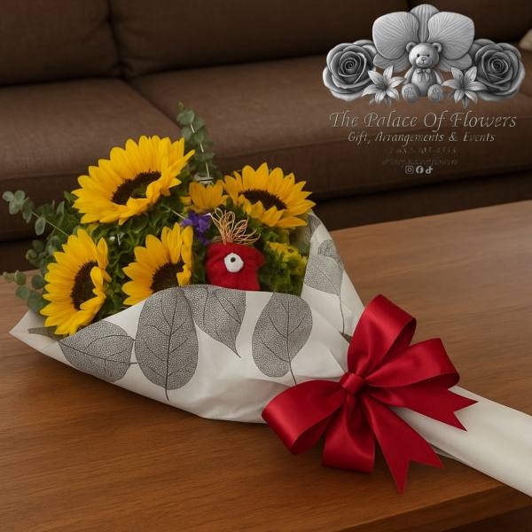 Sunflower bouquet wrapped in leaf-print paper with a red ribbon