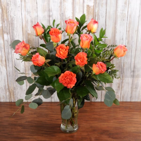 Tall arrangement of orange roses in a clear glass vase