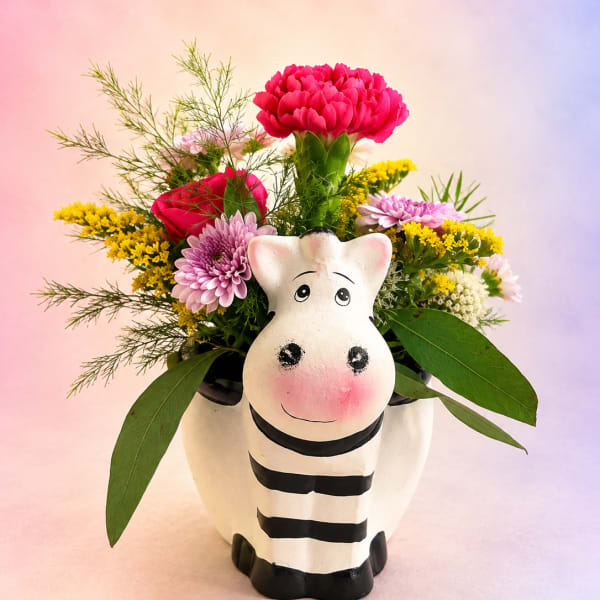 Flower arrangement in a zebra-shaped ceramic container with pink and yellow blooms