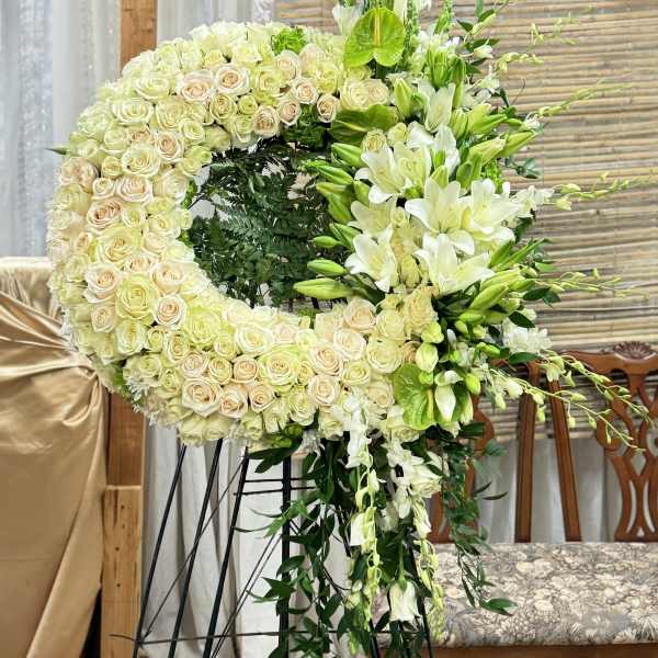 Large floral wreath of white roses and lilies on a stand