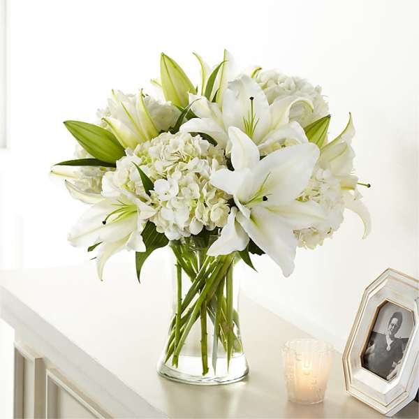 White lilies and hydrangeas in a clear glass vase