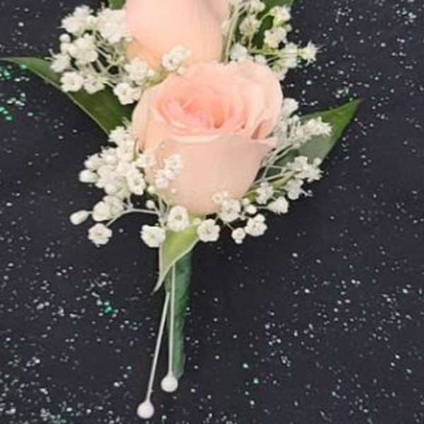 Peach rose boutonniere with white filler flowers on a black speckled background
