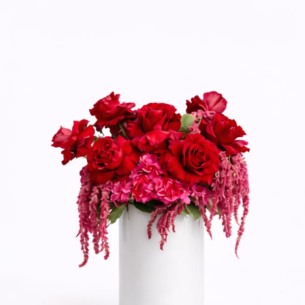 Red rose arrangement in a white cylindrical vase