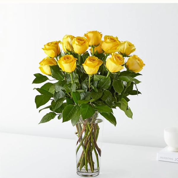 Tall bouquet of yellow roses arranged in a clear glass vase.