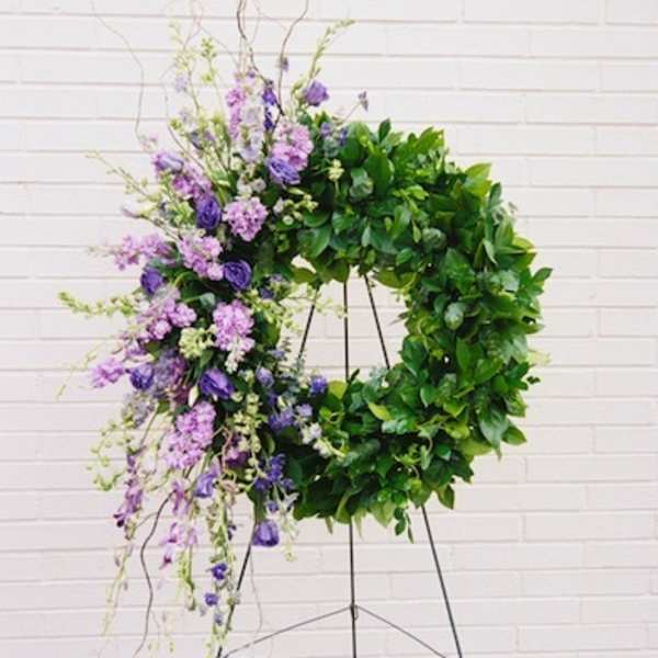 Purple floral wreath on a stand with trailing blooms