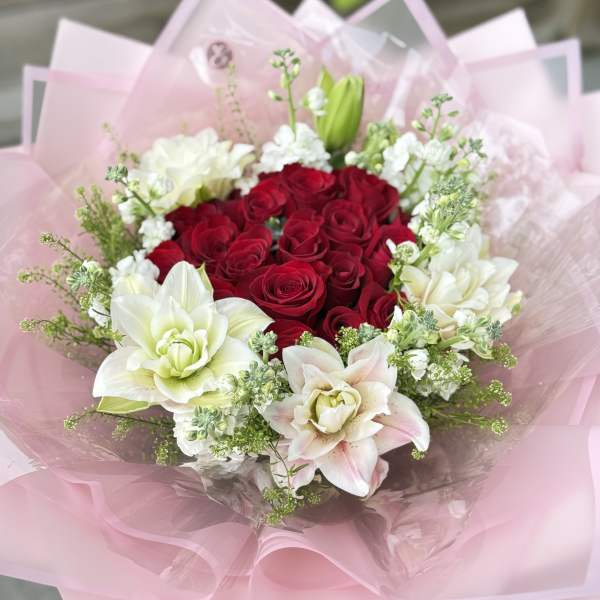 Bouquet of red roses and white lilies wrapped in pink paper