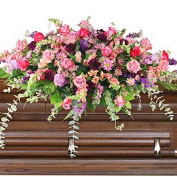 Pink and purple floral spray on a wooden casket