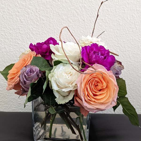 Mixed roses and carnations in a square glass vase