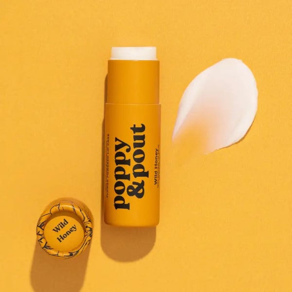 Yellow lip balm tube with a white petal beside it
