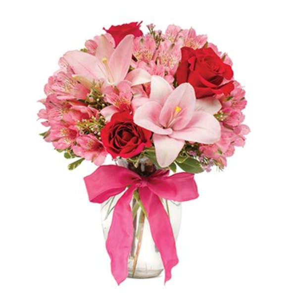 Pink and red bouquet in a clear glass vase with a pink ribbon