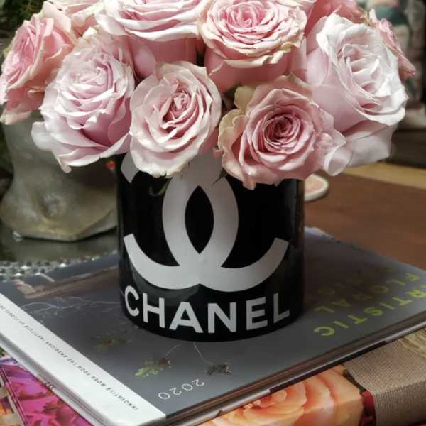 Pink roses arranged in a black Chanel container