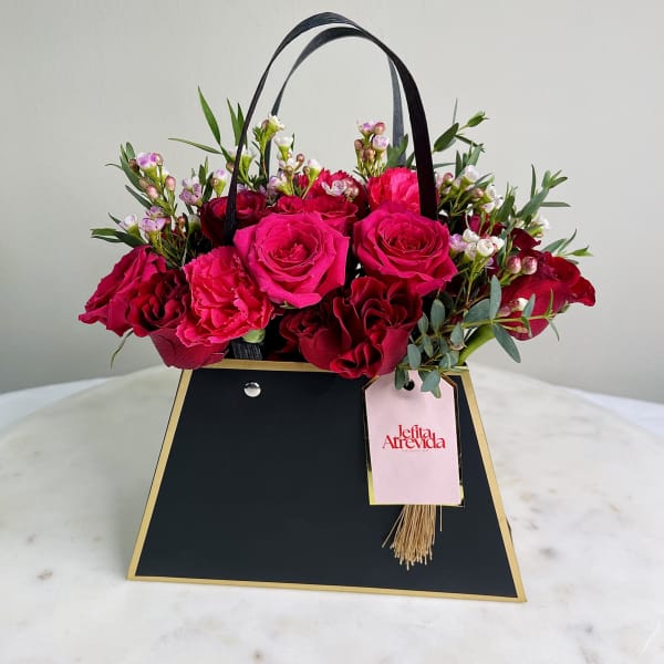 Pink and red roses in a black gift bag with handles