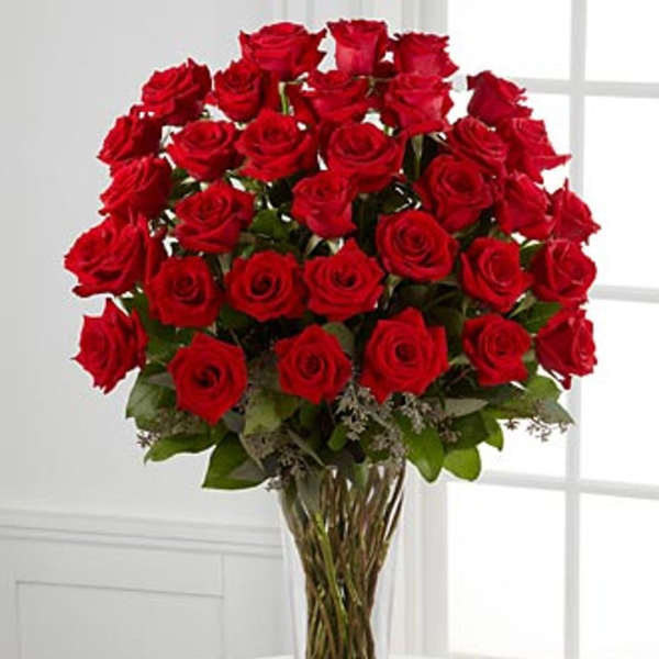 Tall bouquet of red roses in a clear glass vase
