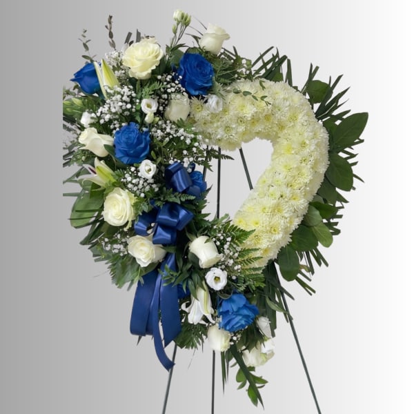 Heart-shaped floral wreath with white and blue roses on a stand