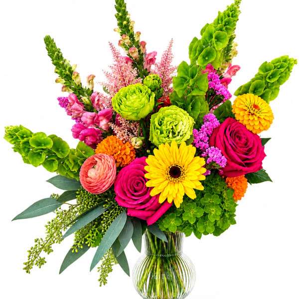 Bright mixed bouquet in a clear glass vase with roses, gerbera daisies, and green blooms