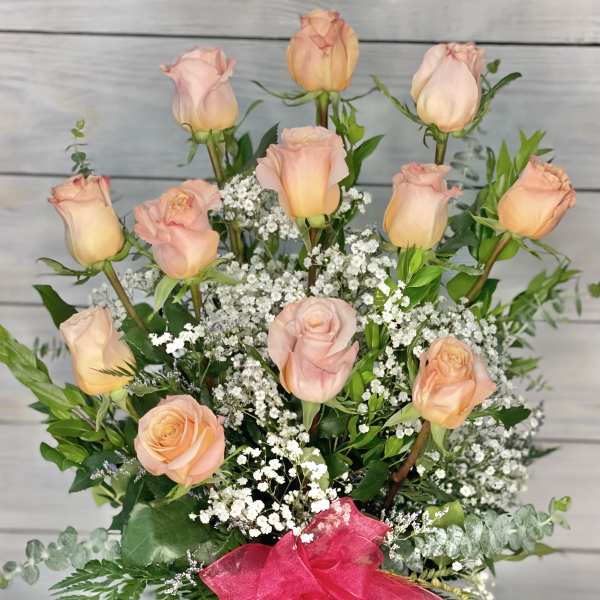 Pink roses and peach roses arranged with baby's breath in a glass vase