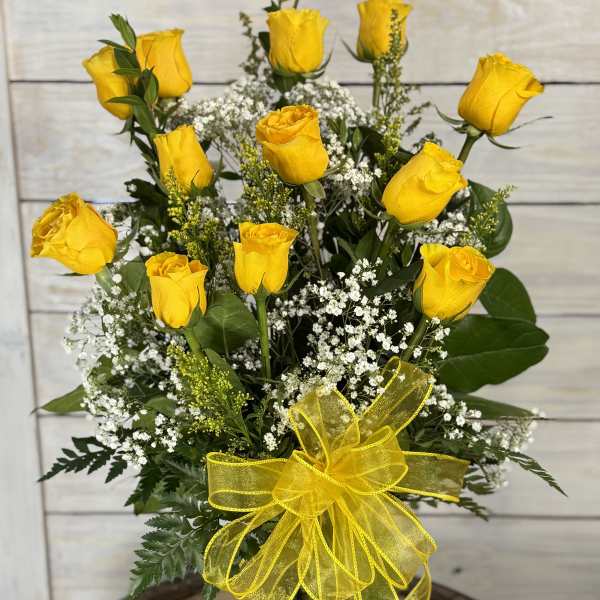 Yellow roses in a glass vase with baby's breath and a yellow ribbon