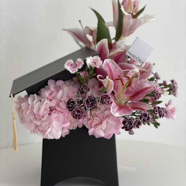Pink lilies and hydrangeas arranged in a black graduation box