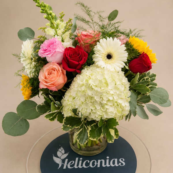 Mixed bouquet of roses, gerbera daisies, and hydrangea in a glass vase
