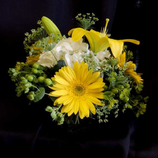 Yellow gerbera daisies and calla lilies with white hydrangea in a vase