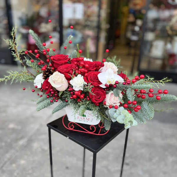 Red and white rose arrangement with berries in a white container