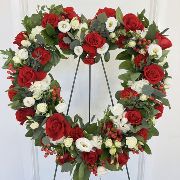 Heart-shaped floral wreath with red and white roses on a stand