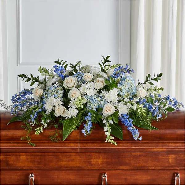 White and blue floral casket spray with roses and hydrangeas