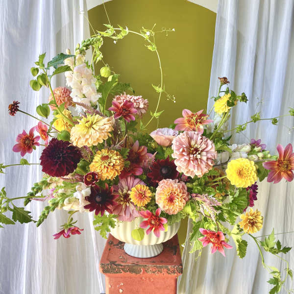 Colorful mixed flower arrangement in a cream vase on a pedestal