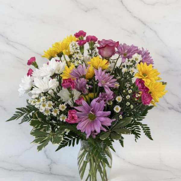 Mixed bouquet of daisies and roses in a clear glass vase
