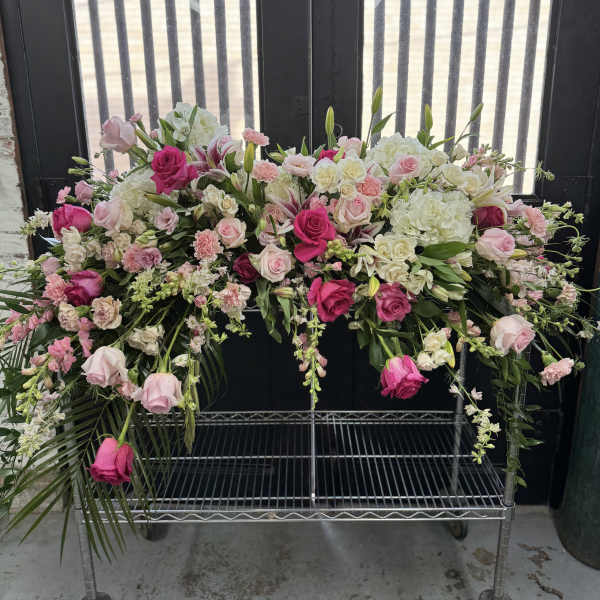 Large pink and white floral spray on a metal cart