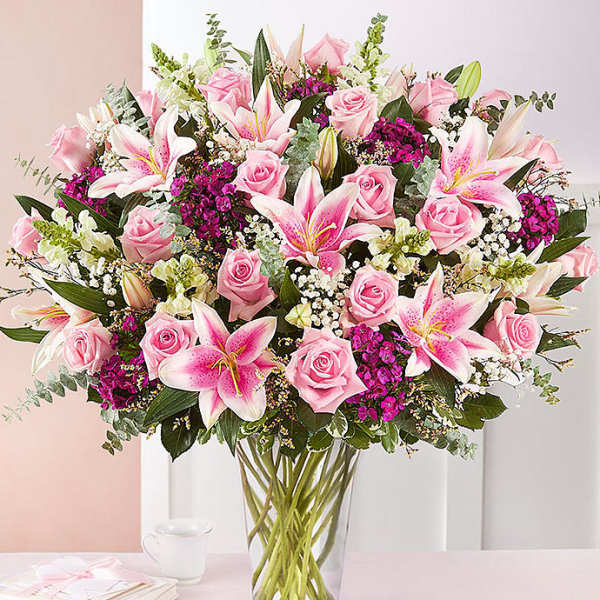 Pink roses and lilies arranged in a clear glass vase