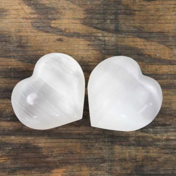 Two white heart-shaped stones on a wooden surface