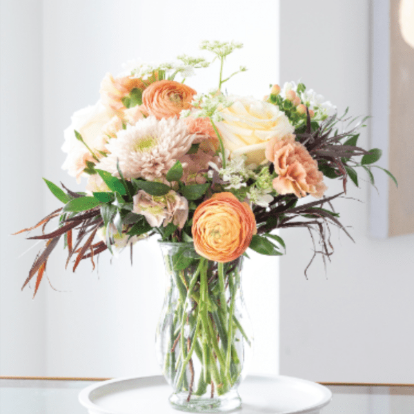 Peach and white flowers arranged in a clear glass vase