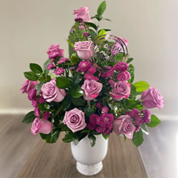 Pink roses and magenta filler flowers in a white vase