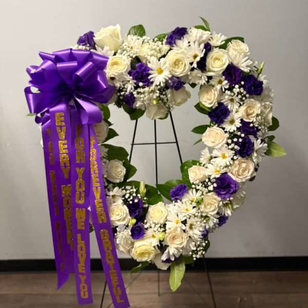 Heart-shaped floral wreath with purple ribbon and white and purple flowers