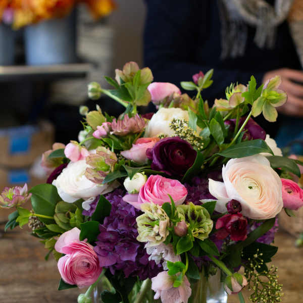 Mixed pink, white, and purple flowers arranged in a clear glass vase