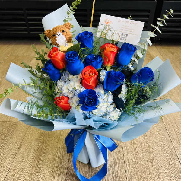 Bouquet of blue and red roses with a small teddy bear and ribbon wrap