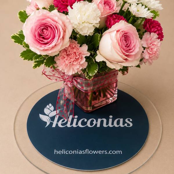 Pink roses and carnations arranged in a square glass vase