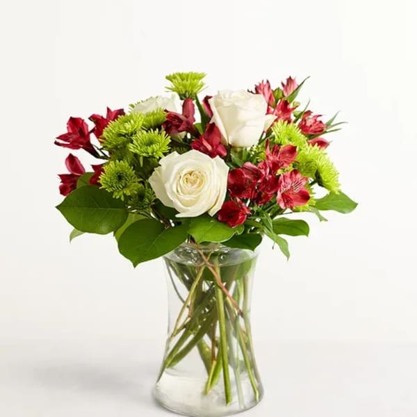 White roses and red alstroemeria in a clear glass vase