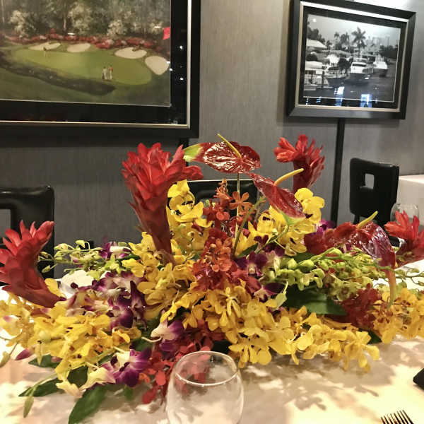 Low tropical centerpiece with red and yellow orchids on a table
