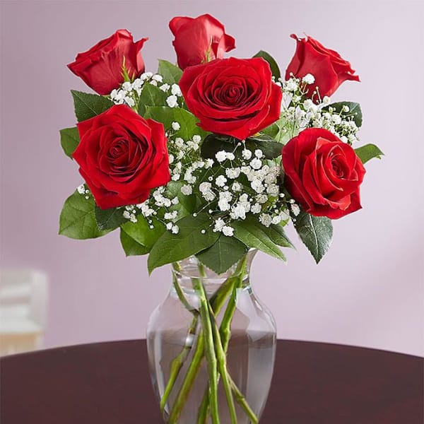 Red roses with baby's breath in a clear glass vase