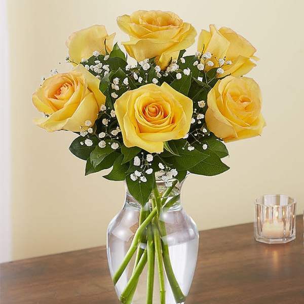Yellow roses arranged in a clear glass vase with baby's breath