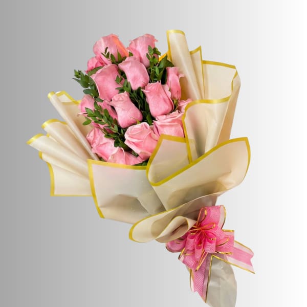 Bouquet of pink roses wrapped in cream paper with yellow trim