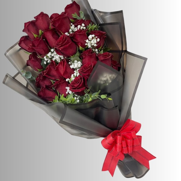 Bouquet of deep red roses wrapped in dark paper with a red ribbon