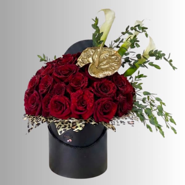 Red roses in a black hatbox with gold calla lilies and greenery