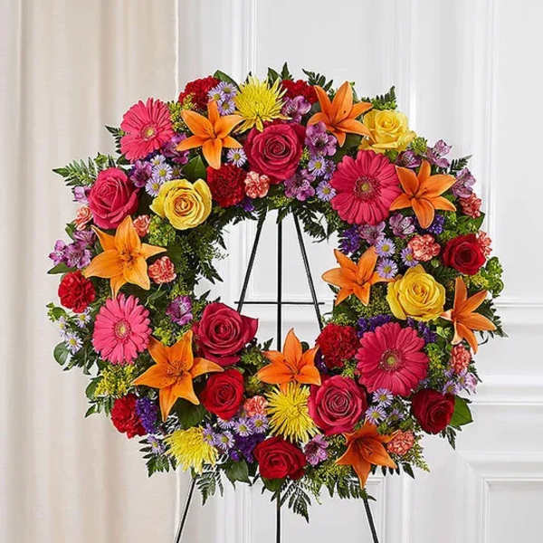 Heart-shaped floral wreath with roses, lilies, and daisies on an easel