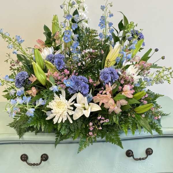 Large pastel floral casket spray with lilies, chrysanthemums, and blue delphinium